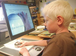 a photo of a boy using AT to use a computer