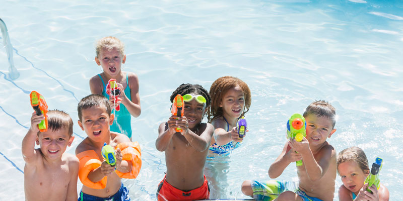 a photo of kids playing in a pool with water pistols