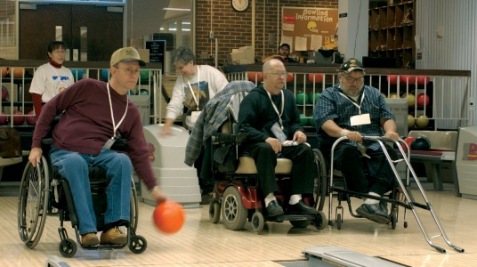 three men in wheelchairs bowling