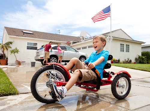 a photo of a boy riding the Three Wheeled Cruiser in his family's driveway