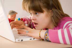 a photo of a girl with down syndrom working on a MacBook