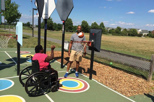 a photo of a father and son playing basketball. The son is using a wheelchair