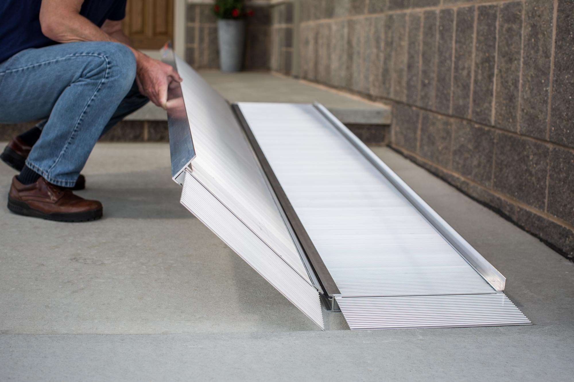 a photo of a portable wheelchair ramp being laido down over a step